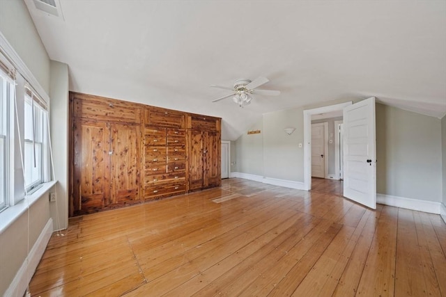 additional living space featuring visible vents, light wood-style flooring, a ceiling fan, baseboards, and vaulted ceiling