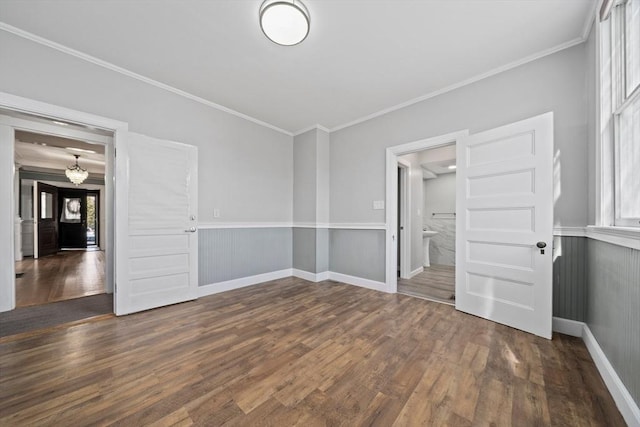 unfurnished room featuring a wainscoted wall, crown molding, baseboards, and wood finished floors