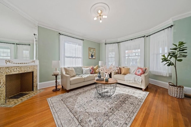 living area featuring crown molding, wood finished floors, baseboards, and a premium fireplace