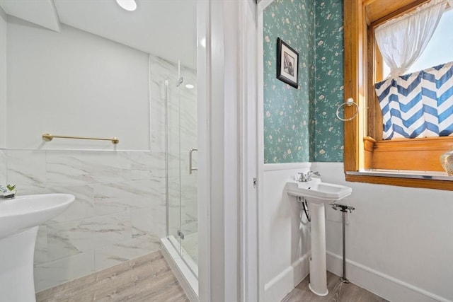 full bathroom featuring a wainscoted wall, wood finished floors, a stall shower, and wallpapered walls