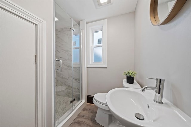 full bathroom featuring a marble finish shower, visible vents, toilet, wood finished floors, and a sink