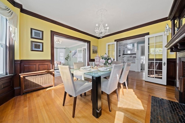 dining area with radiator, crown molding, wainscoting, an inviting chandelier, and wood finished floors