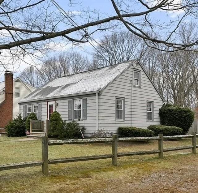 view of front of property featuring a shingled roof, a front yard, and fence