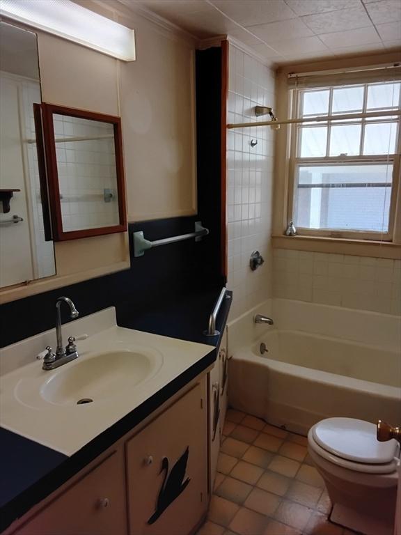 bathroom with toilet, shower / bath combination, tile patterned flooring, and vanity