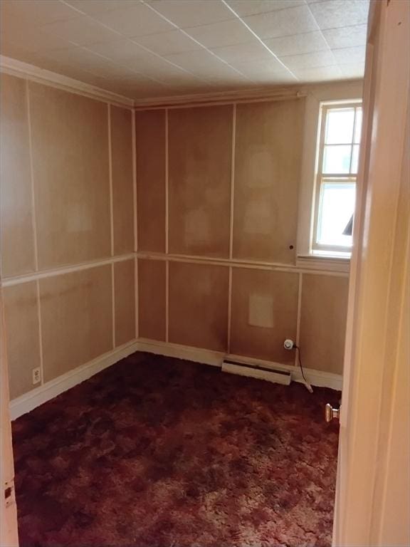 empty room featuring a baseboard radiator and dark carpet