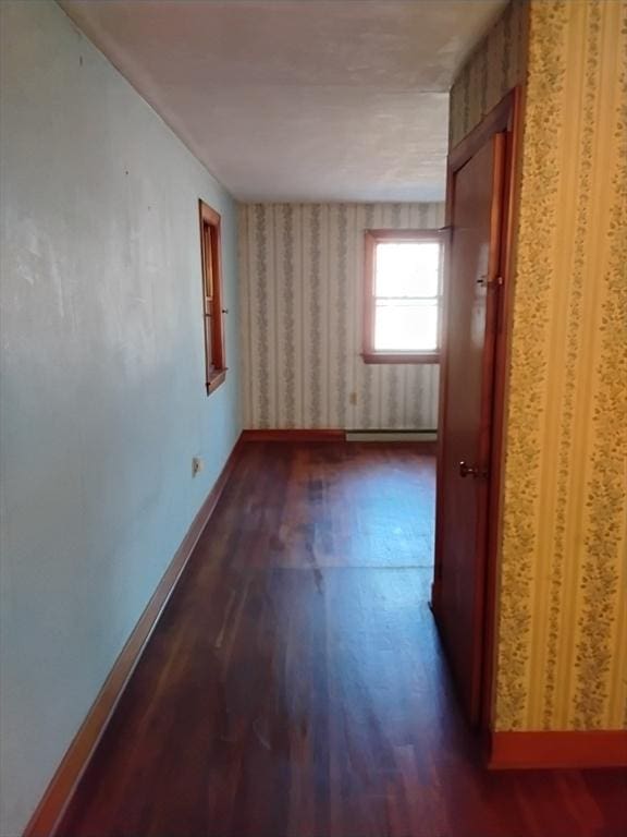 spare room featuring dark wood-style flooring and baseboards