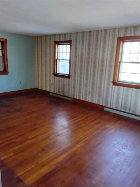 unfurnished room featuring wallpapered walls, a baseboard radiator, plenty of natural light, and baseboards