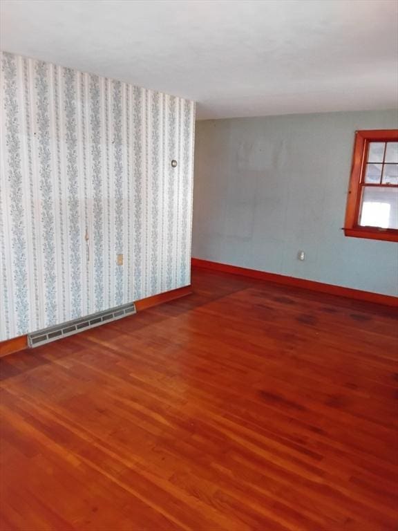 spare room with visible vents, baseboards, and wood finished floors