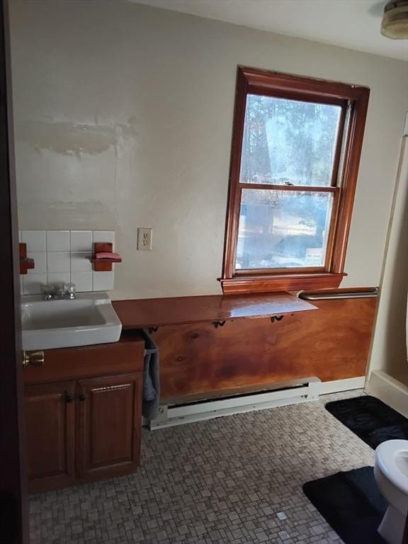 bathroom featuring a baseboard heating unit, toilet, and vanity