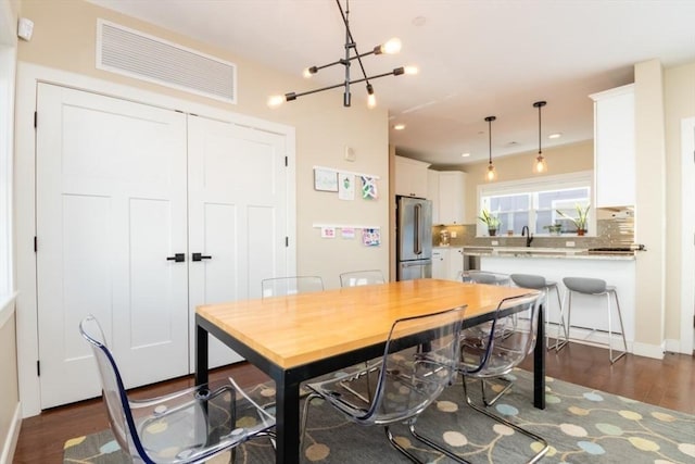 dining space featuring visible vents, an inviting chandelier, and dark wood finished floors