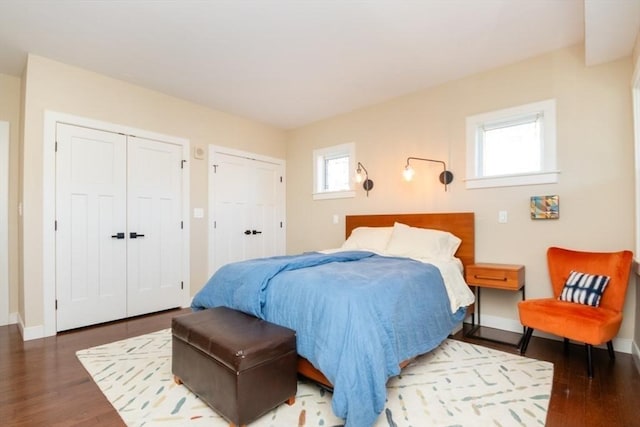 bedroom featuring baseboards, two closets, and wood finished floors