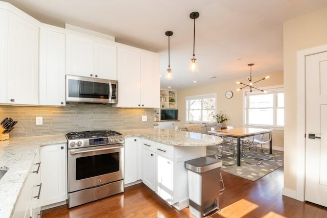 kitchen with a peninsula, stainless steel appliances, decorative backsplash, dark wood-type flooring, and white cabinets