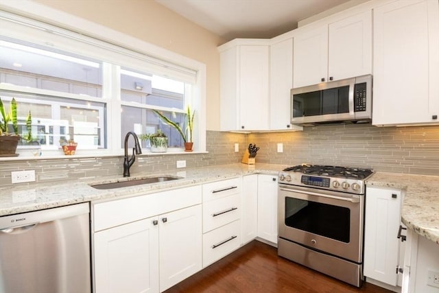 kitchen with dark wood-style floors, a sink, decorative backsplash, stainless steel appliances, and white cabinetry