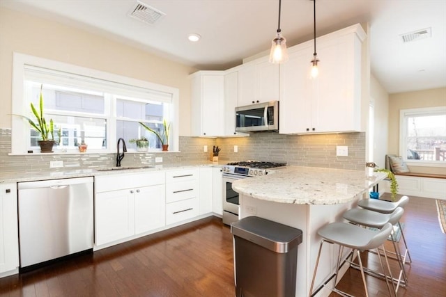 kitchen featuring visible vents, appliances with stainless steel finishes, a peninsula, and a sink