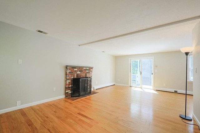 unfurnished living room featuring wood finished floors, baseboards, and a brick fireplace