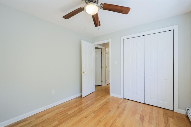 unfurnished bedroom featuring light wood-style flooring, baseboards, a baseboard radiator, a ceiling fan, and a closet