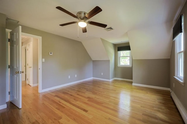 bonus room featuring a baseboard radiator, light wood finished floors, baseboards, a ceiling fan, and lofted ceiling