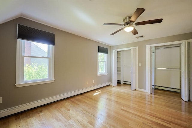 unfurnished bedroom featuring a baseboard radiator, baseboard heating, multiple closets, light wood finished floors, and baseboards