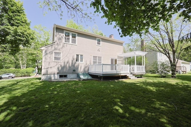 rear view of property with a wooden deck, a chimney, and a yard