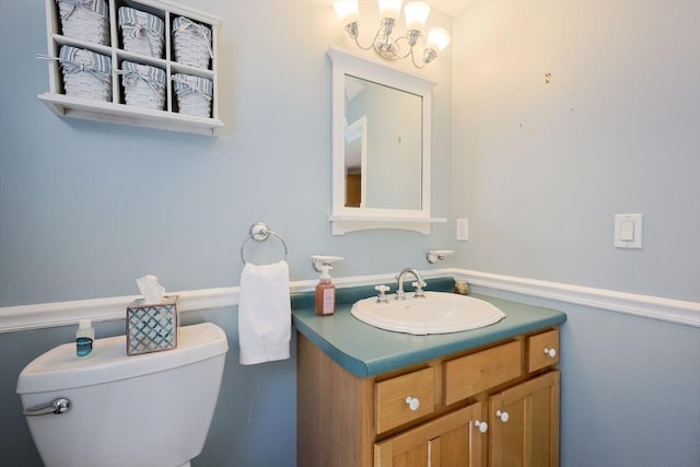 half bathroom with a chandelier, toilet, and vanity