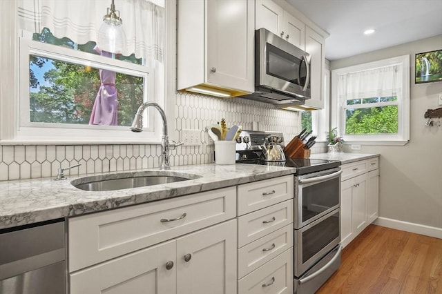 101 Eastern Ave, Woburn, MA 01801 - kitchen with stainless steel appliances, decorative backsplash, light wood-style floors, white cabinetry, and recessed lighting