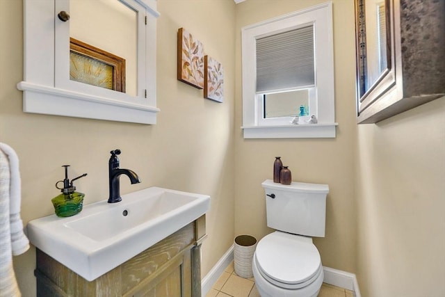 half bath featuring baseboards, vanity, toilet, and tile patterned floors