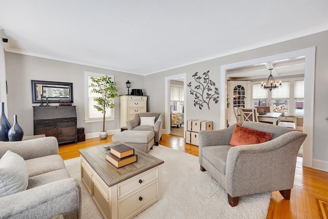 living room featuring an inviting chandelier, baseboards, and light wood-style floors