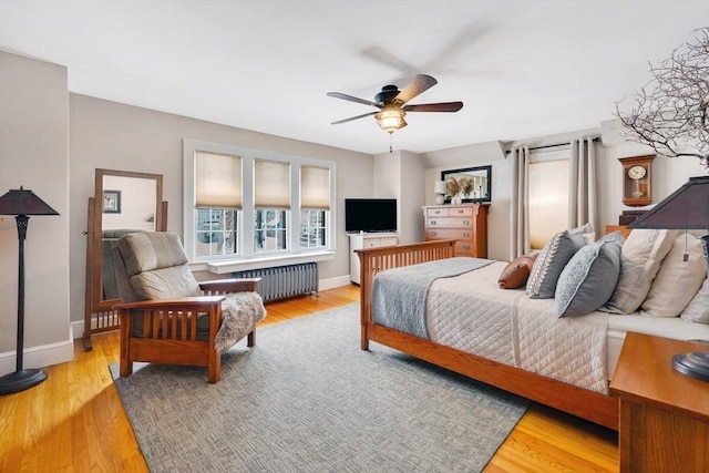 bedroom with baseboards, wood finished floors, and radiator