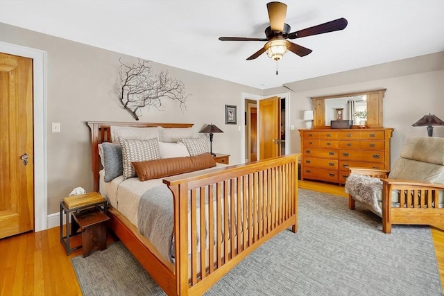 bedroom with ceiling fan, wood finished floors, and baseboards