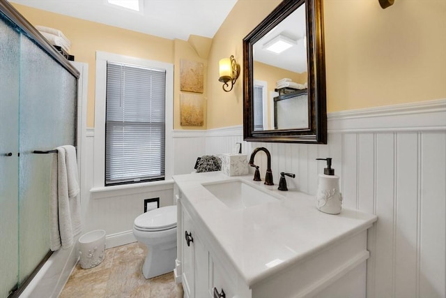 full bathroom with a wainscoted wall, vanity, toilet, and an enclosed shower