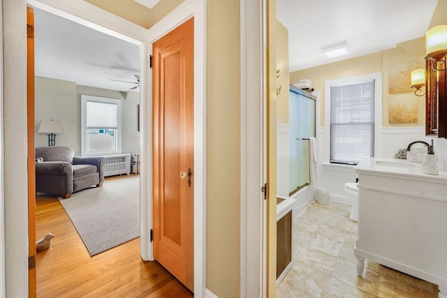 bathroom with toilet, vanity, wood finished floors, and wainscoting