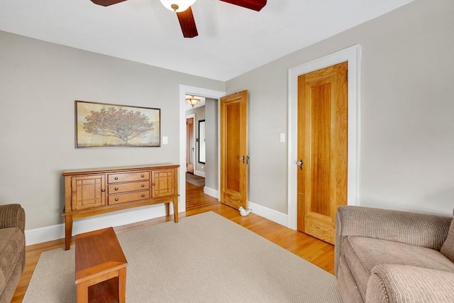 living area with light wood-type flooring, ceiling fan, and baseboards