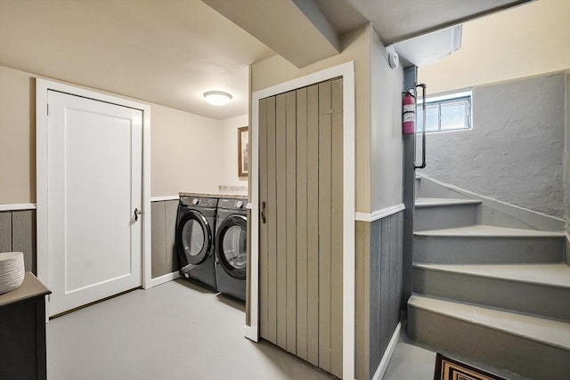 washroom with a wainscoted wall, washing machine and dryer, and cabinet space