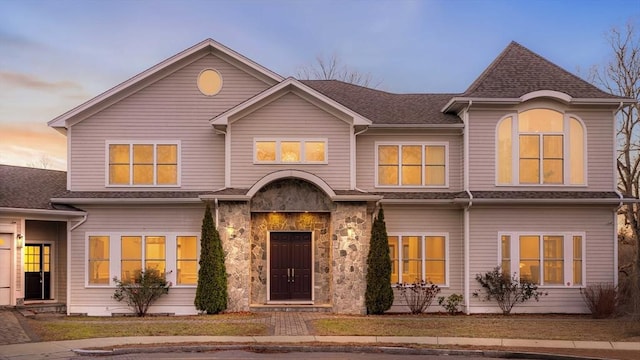 view of front facade with a shingled roof and stone siding