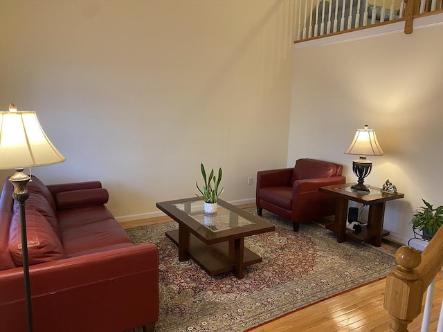 living area with baseboards, a high ceiling, and wood finished floors