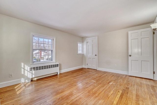 spare room with light wood finished floors, radiator heating unit, and baseboards