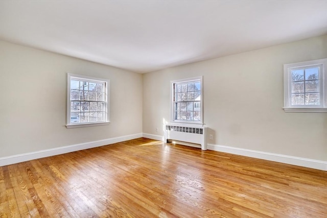 spare room with light wood finished floors, radiator, and baseboards