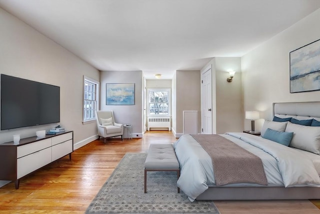 bedroom with baseboards, radiator, and light wood finished floors