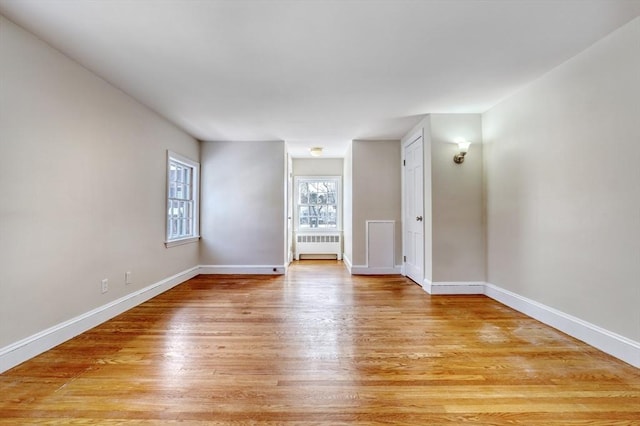 unfurnished room with light wood-style flooring, radiator heating unit, and baseboards