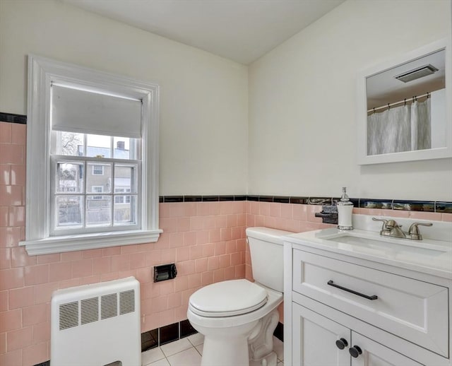 full bath with vanity, radiator, tile patterned floors, toilet, and tile walls