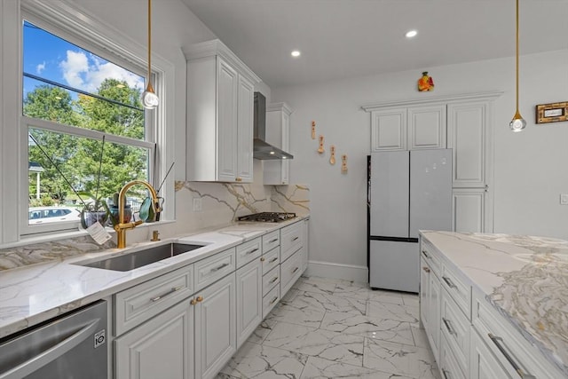 kitchen with stainless steel appliances, a sink, white cabinets, wall chimney range hood, and marble finish floor