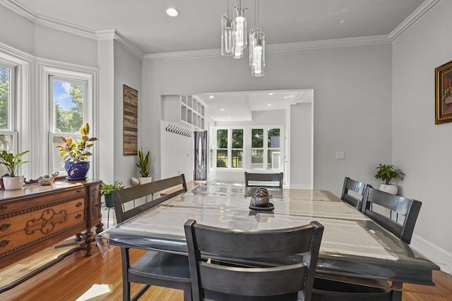 dining space with plenty of natural light, crown molding, and wood finished floors