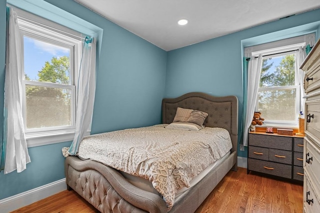 bedroom featuring multiple windows, baseboards, and wood finished floors