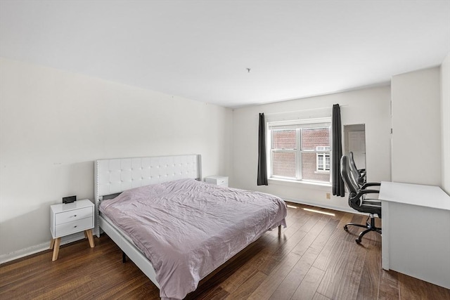 bedroom featuring dark wood-style flooring, an office area, and baseboards