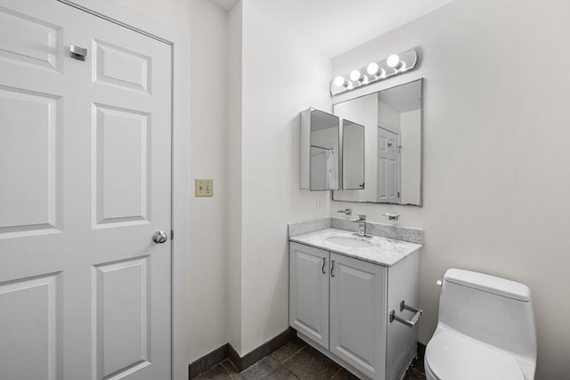 bathroom featuring toilet, vanity, and baseboards