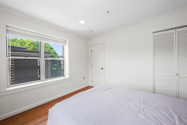 bedroom featuring wood finished floors, baseboards, a closet, and recessed lighting