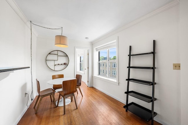 dining space with ornamental molding, light wood finished floors, and baseboards