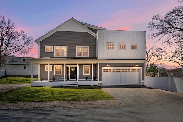 view of front facade with a garage, a porch, and a lawn