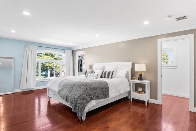 bedroom with a closet, dark hardwood / wood-style floors, a spacious closet, and crown molding