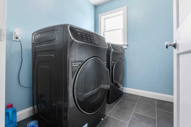 clothes washing area with washing machine and dryer and dark tile flooring